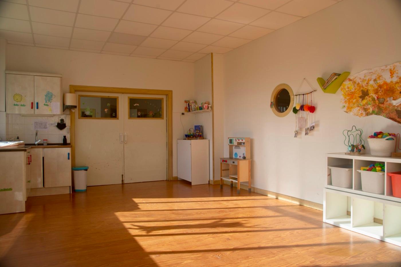 Aula de 1 a 2 años, con el suelo de madera y el rincón de la cocinita