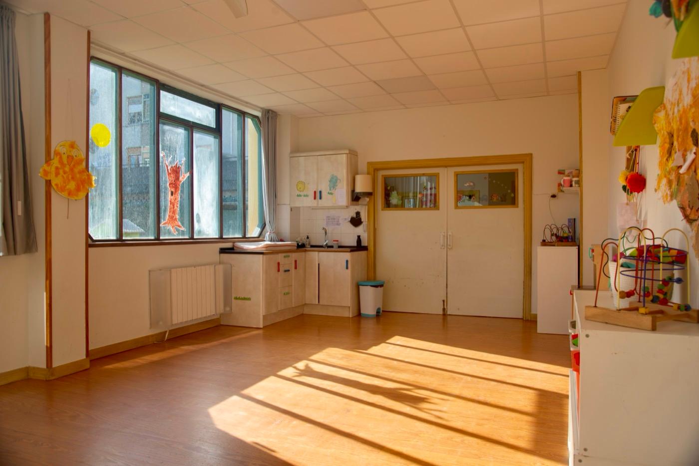 Aula de 1 a 2 años con la ventana grande y el sol entrando por el suelo