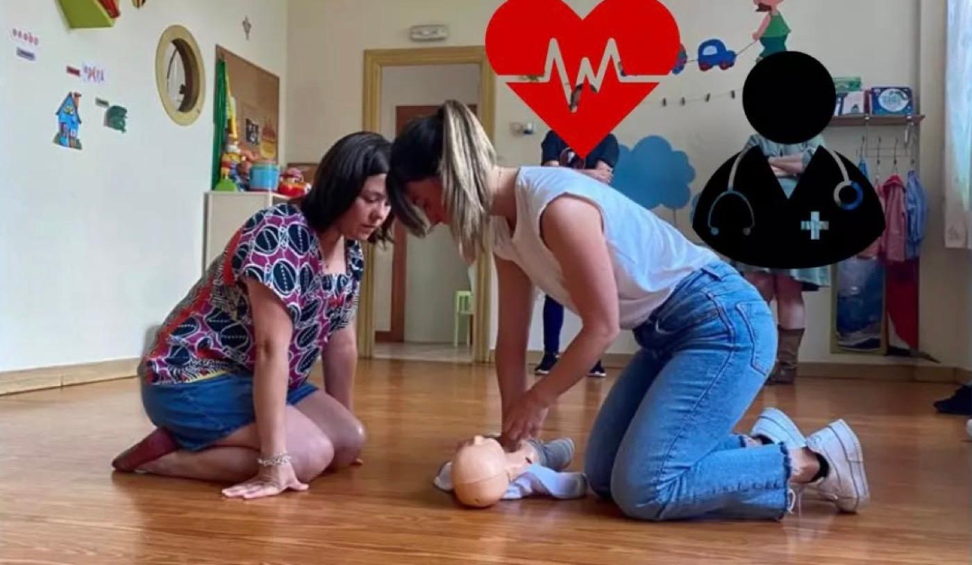 Dos educadoras practicando la reanimación con un muñeco de bebé en el taller de primeros auxilios