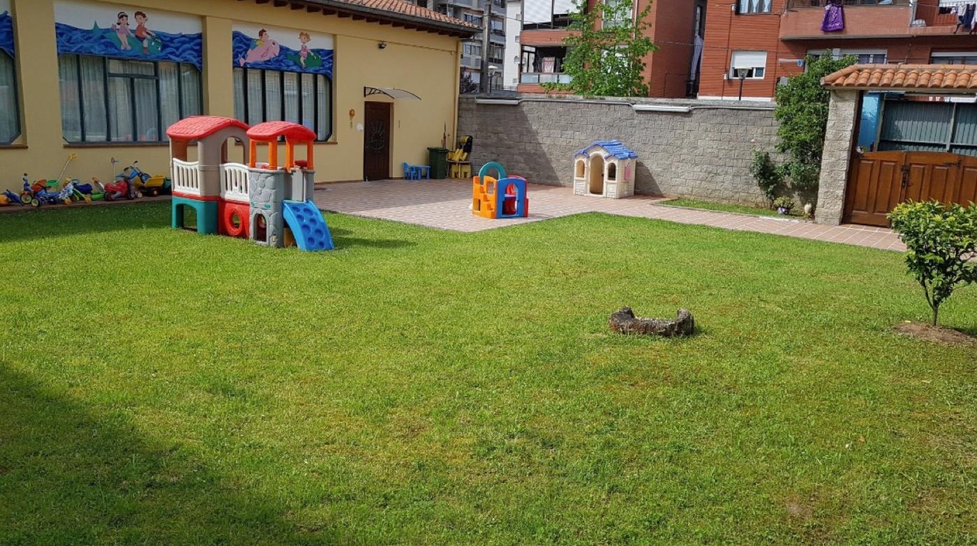 El patio de césped con los juegos, el tobogán y la casita de madera